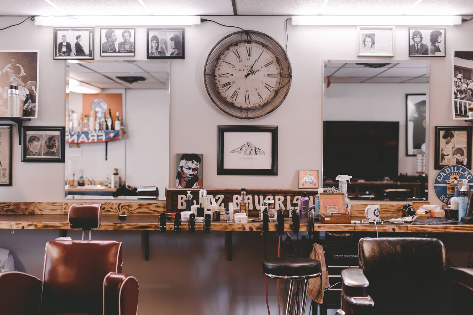 Interior de la barbería: la repisa de madera bajo los espejos, las sillas de cuero rojo y las fotos enmarcadas en la pared.