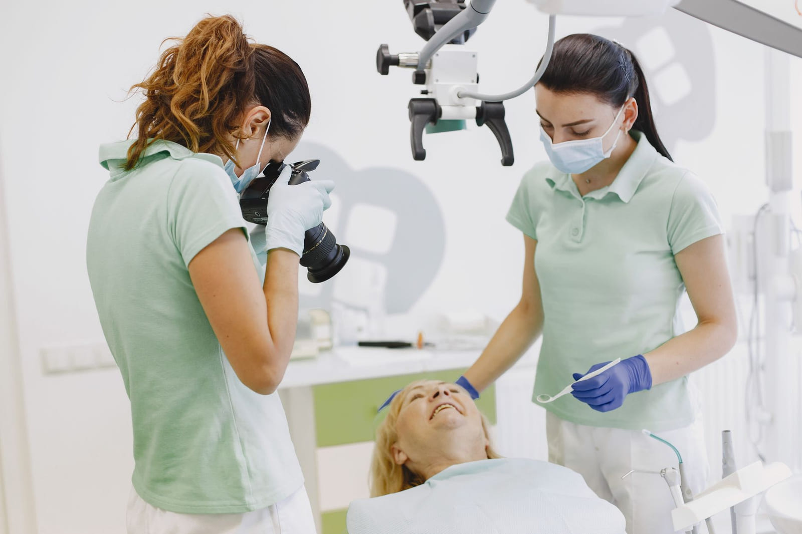 A dentist and an assistant working side by side at the chair in a treatment room.