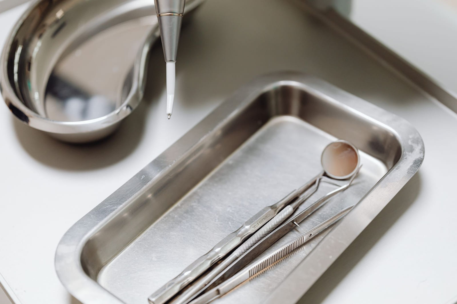 A tray of steel dental instruments laid out in order on a clean surface.