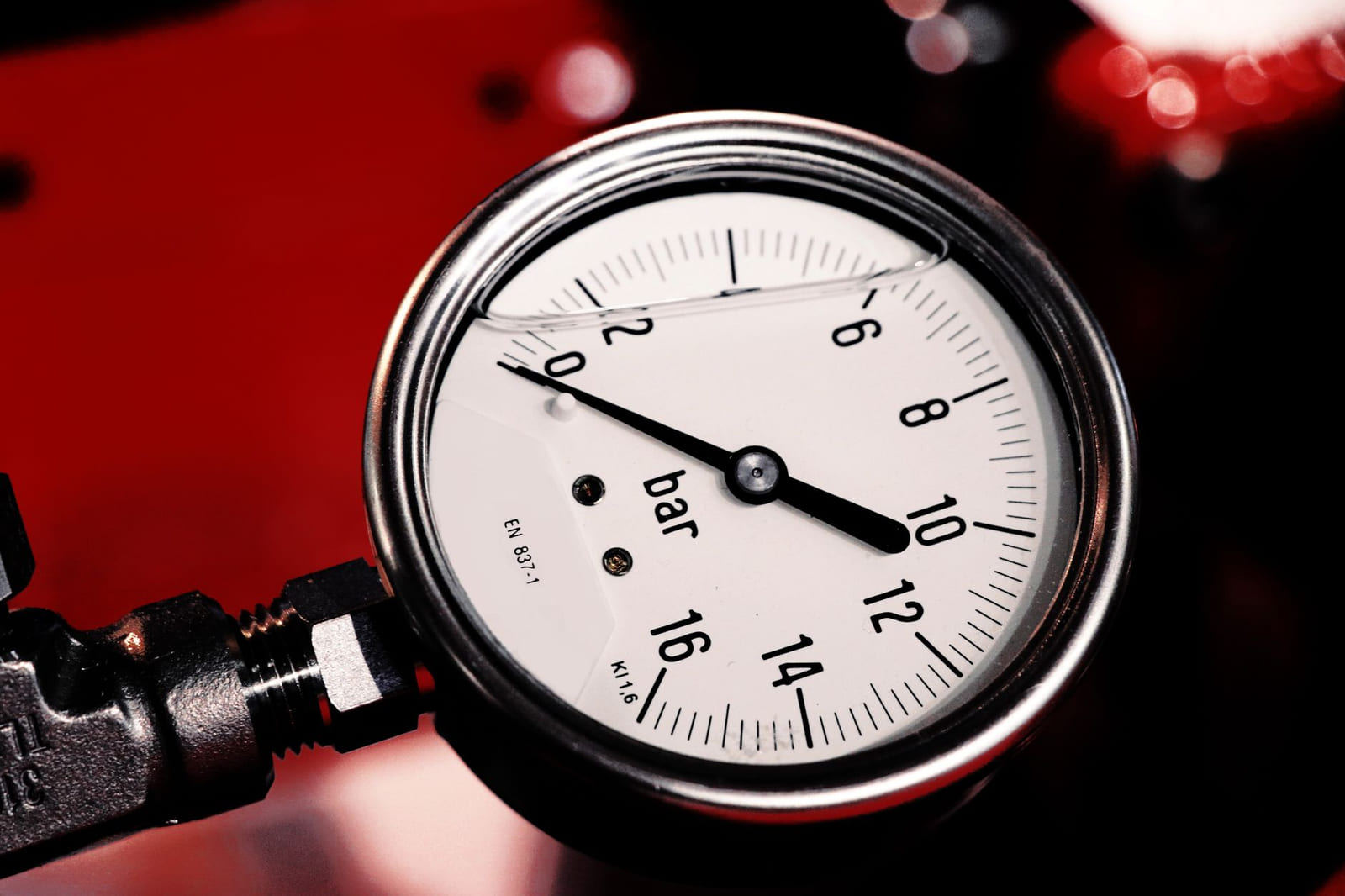 Close-up of a weathered brass-bezel pressure gauge mounted on wellhead piping.