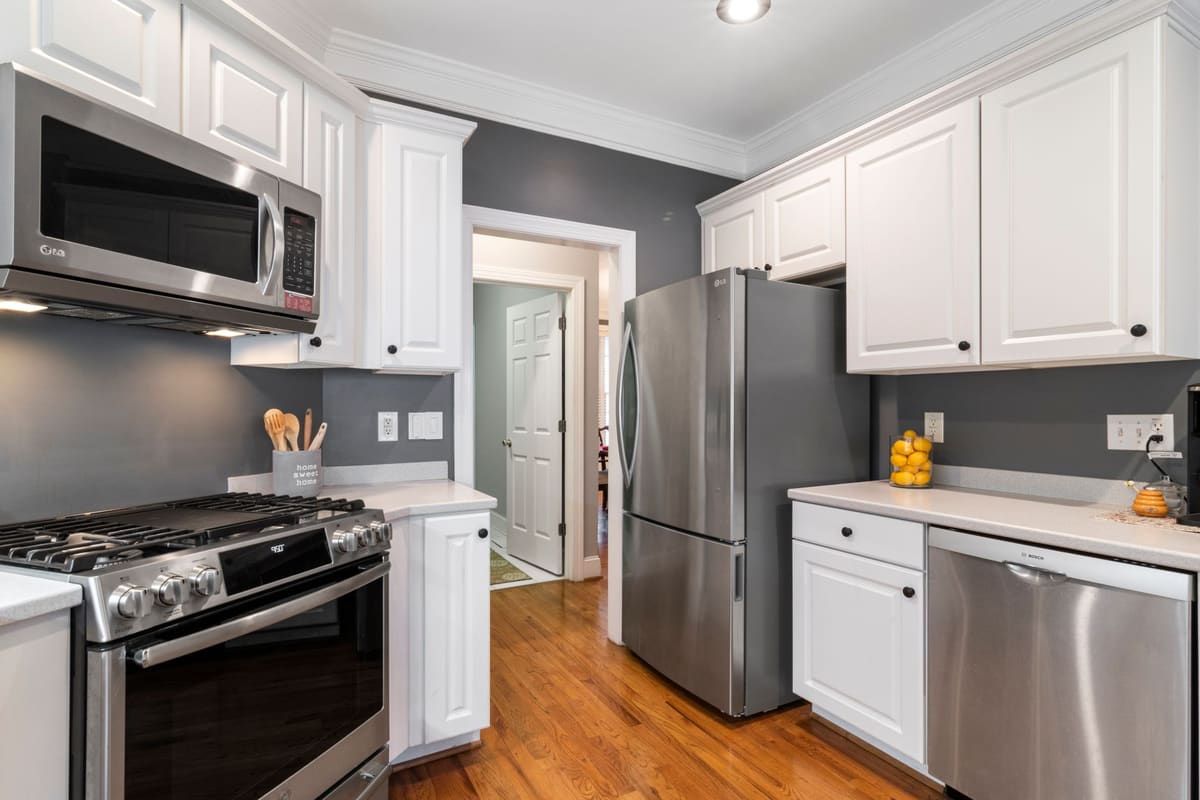 The finished Oak Forest kitchen: white cabinets against charcoal walls, stainless appliances and refinished oak floors.